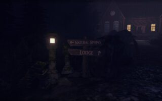 A lamp post and a wooden signpost beside a dark path at night, with the lit windows of a lodge glowing through the fog behind them.
